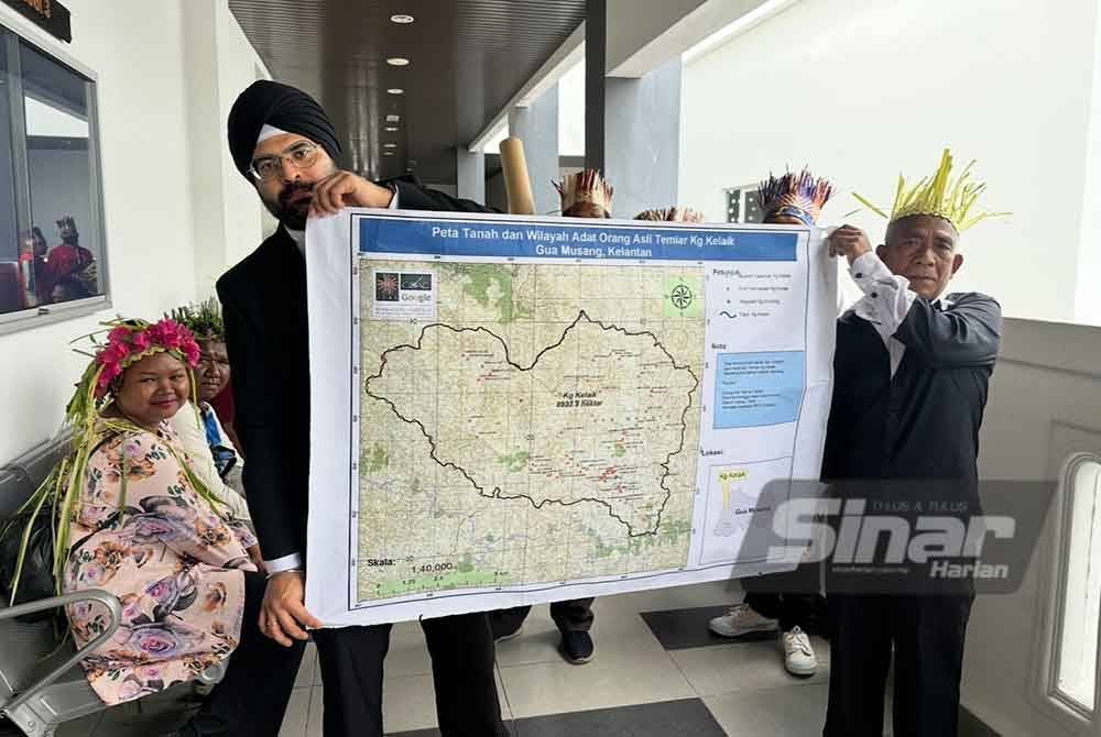 Sachpreetraj (dua dari kanan) dan Ahak (kanan) memegang peta tanah adat Kampung Kelaik, Gua Musang. FOTO SINAR HARIAN-ADILA SHARINNI WAHID