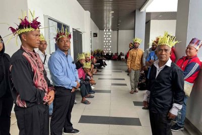 Ahak (kanan) Aziz (dua dari kiri) dan Anjang (kiri) bersama penduduk berada di luar bilik Mahkamah Tinggi Kota Bharu pada Isnin.