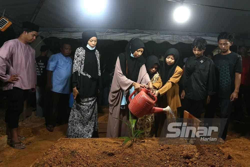 Ibu Allahyarham menyiram air di pusara Allahyarham yang selamat dikebumikan pada jam 12.40 tengah malam.