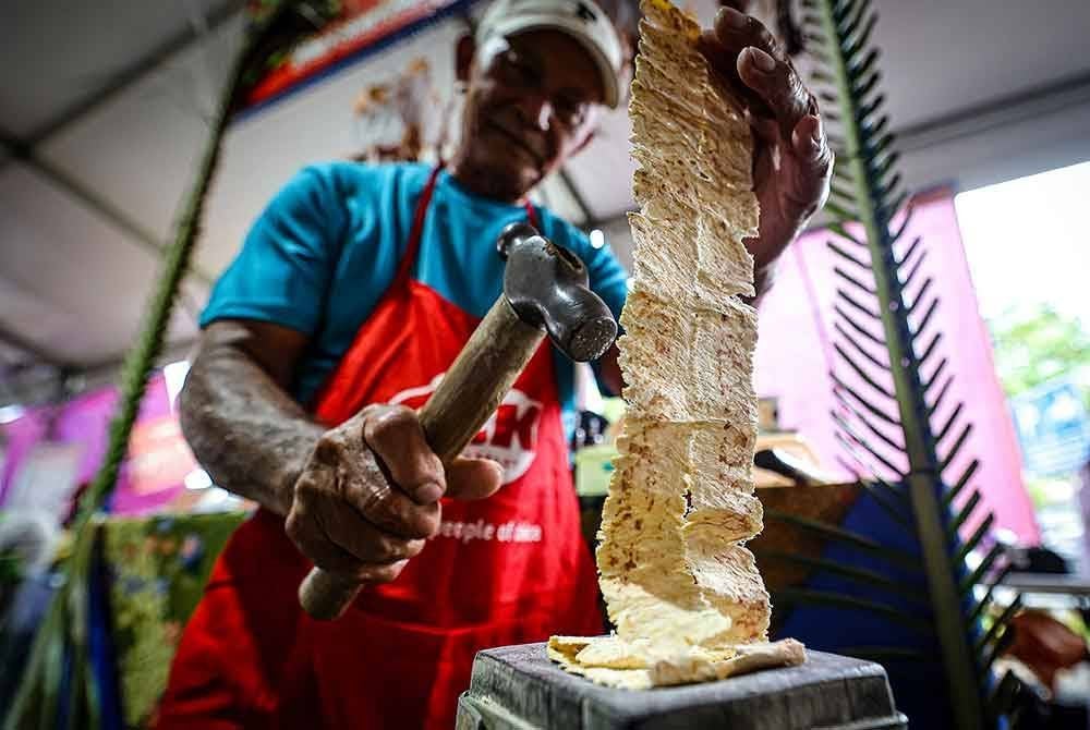 Pengusaha sotong tutok, Salim Brahim, 65, menukul sotong kering sehingga nipis dengan beralaskan kayu belian sebelum dibakar atas bara arang di gerainya di Bazar Ramadan Kubah Ria.