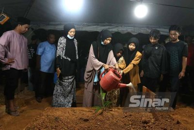 Ibu Allahyarham menyiram air di pusara Allahyarham yang selamat dikebumikan pada jam 12.40 tengah malam.