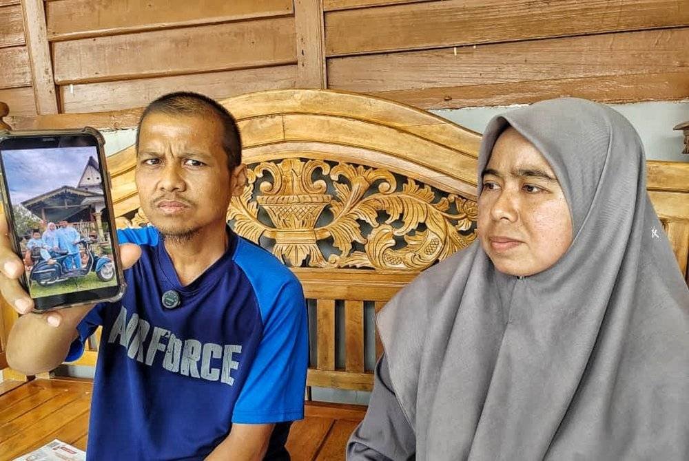 Mohamad Nasirudin (kiri) menunjukkan gambar kenangan mereka sekeluarga meraikan Aidilfitri tahun lalu.