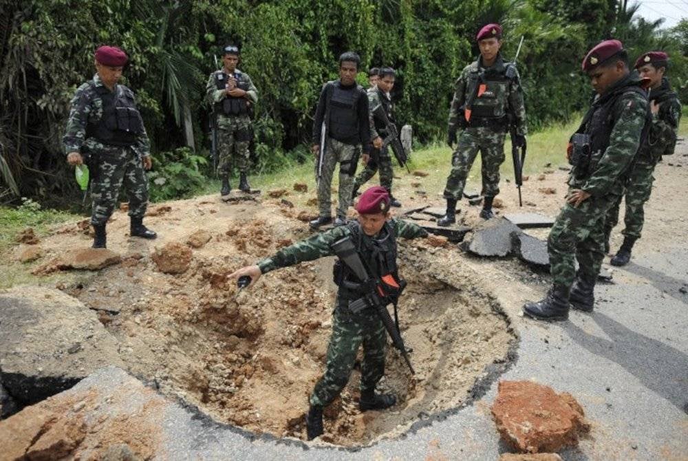 Anggota tentera Thailand memeriksa lokasi serangan bom tepi jalan yang menyasarkan trak tentera di wilayah bergolak Narathiwat.