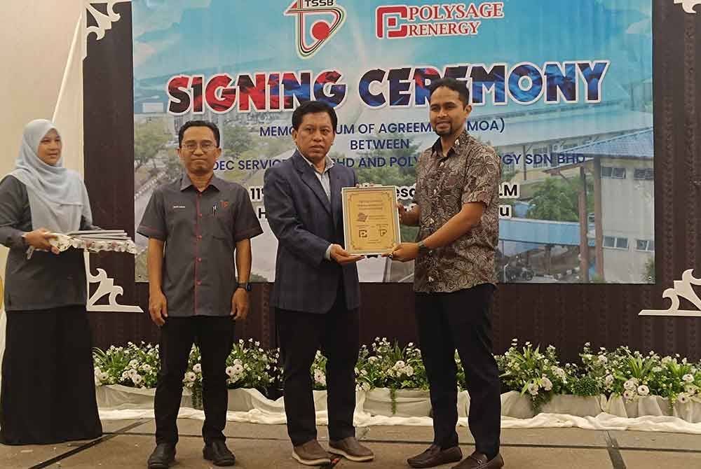 Mohd Azrin (kiri) ketika majlis penyerahan sijil kepada salah seorang penerima selepas majlis menandatangani MoU di sebuah hotel di Kuala Terengganu.