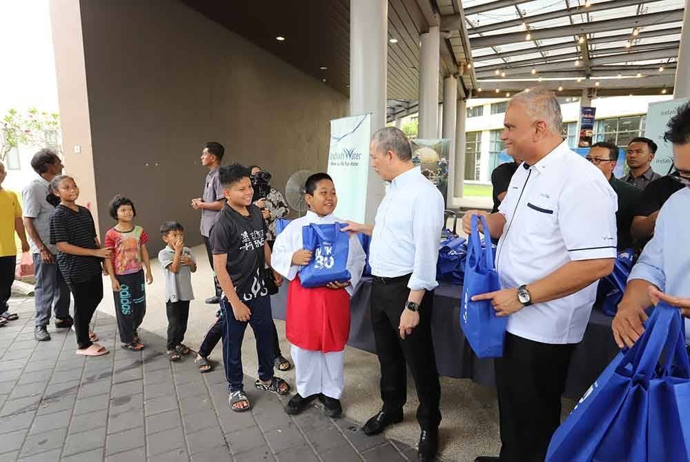 Fadillah (dua dari kanan) bersama Narendran (kanan) dan kakitangan IWK mengagihkan 500 beg makanan kepada penduduk sebagai hidangan berbuka puasa.