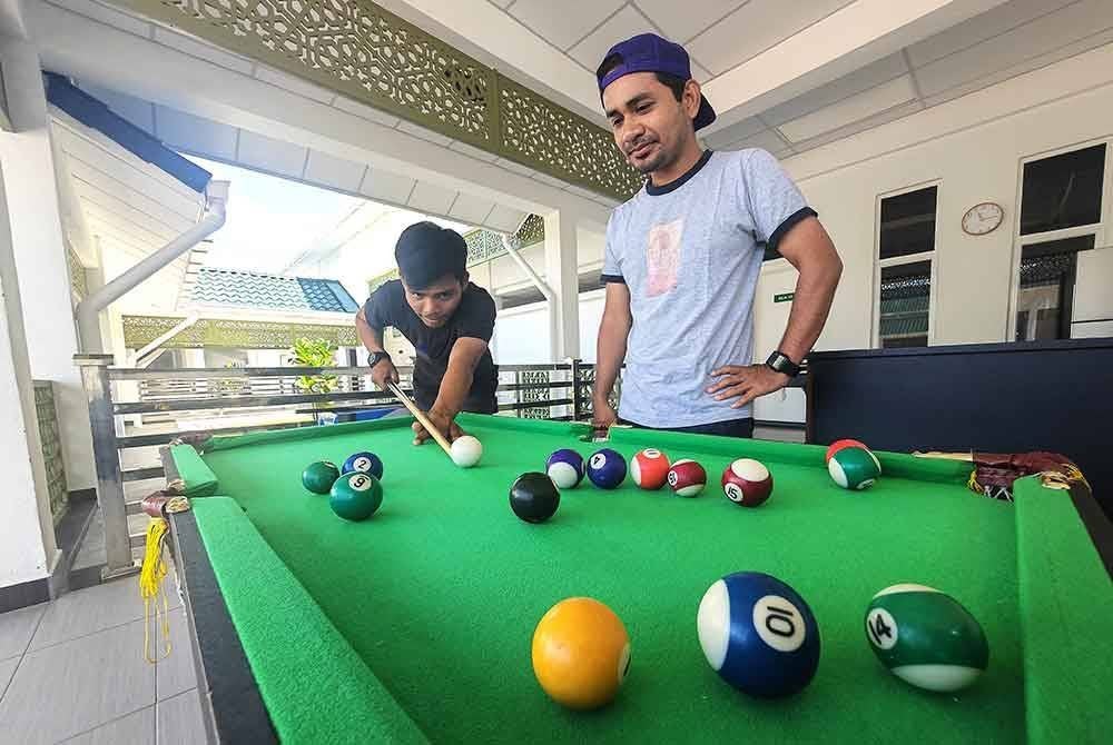 Muhammad (kiri) dan rakannya mengisi waktu sebelum solat dengan bermain snuker di masjid.