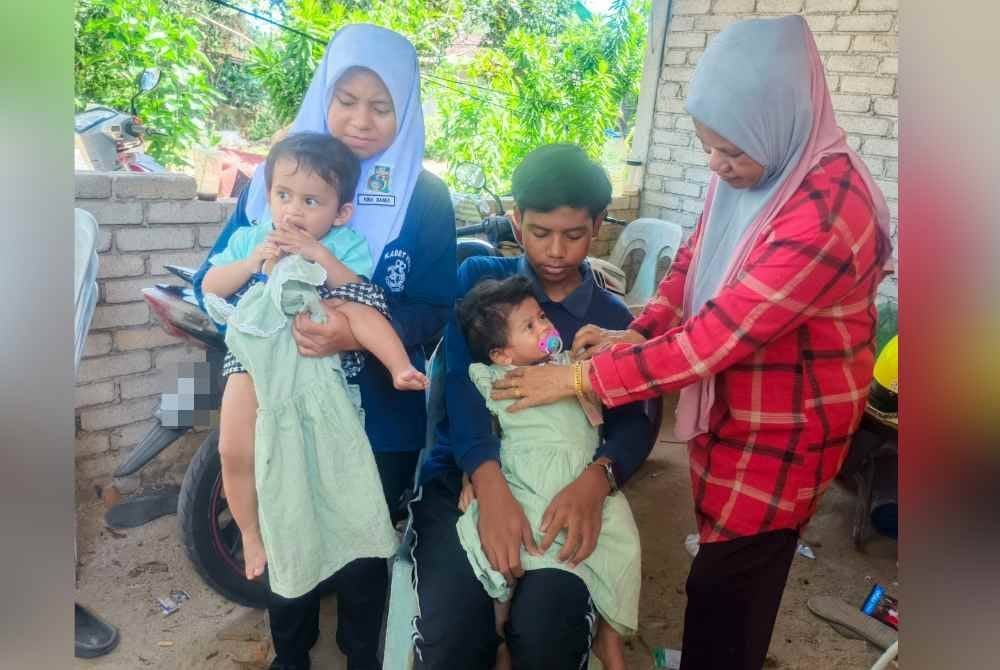 Zuraina (kanan) bersama empat anak saudara yang kini di bawah jagaannya ditemui di Kampung Telok Jamat, Alor Setar pada Rabu.