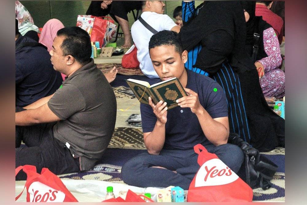 Seorang pengunjung mengisi masa sebelum berbuka puasa dengan membaca al-Quran.