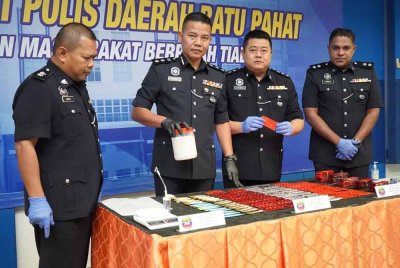 Shahrulanuar (dua dari kiri) menunjukkan bekas yang mengandungi dadah.