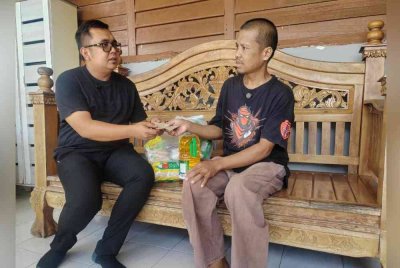 Ashwad (kiri) menyampaikan sumbangan wang tunai daripada Sukarelawan Bencana Melaka.
