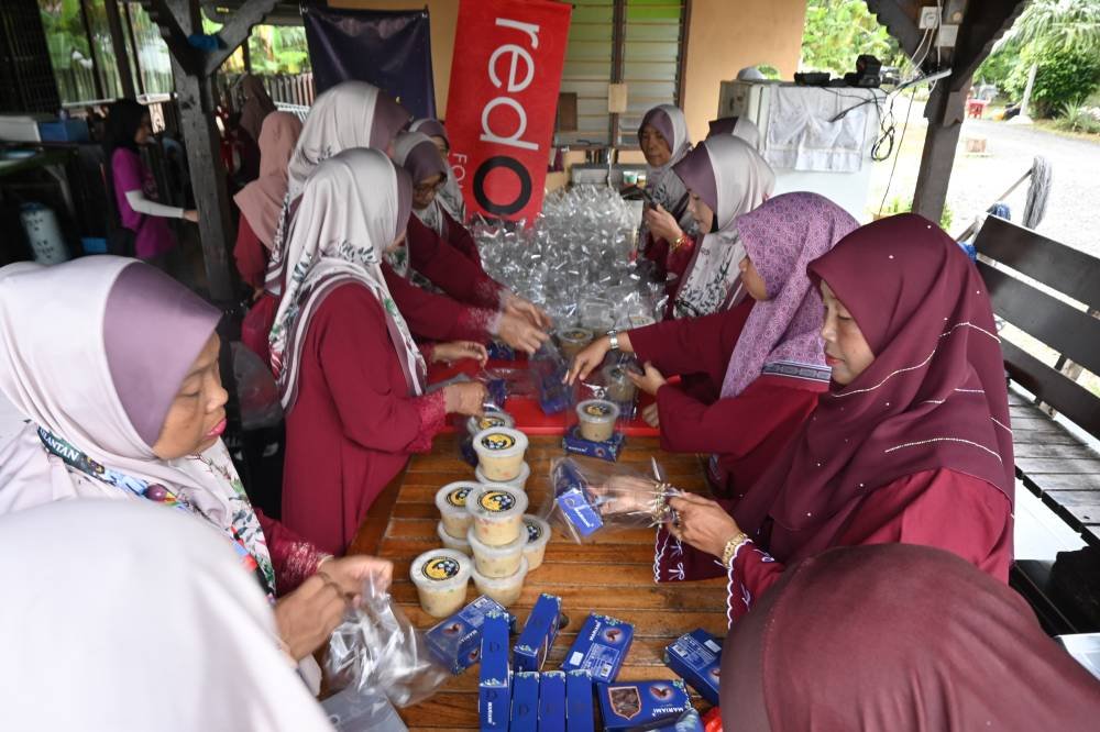 Siti Arbaah bersama AJK surau wanita membungkus bubur lambuk untuk diagihkan.