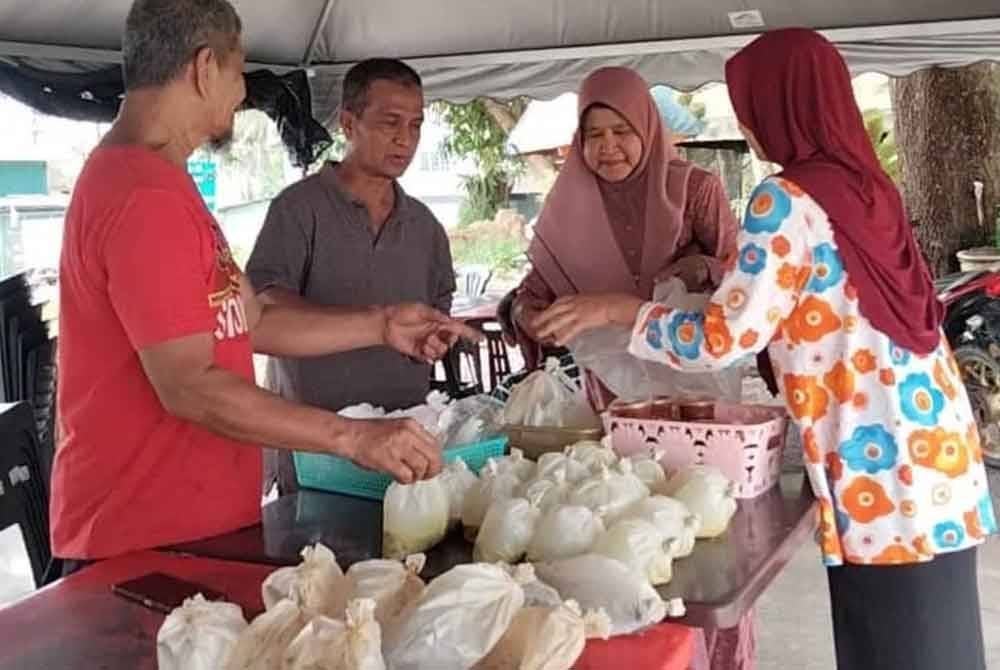 Poksu (kiri) melayani pelanggan yang datang ke gerainya untuk mendapatkan lauk salai.