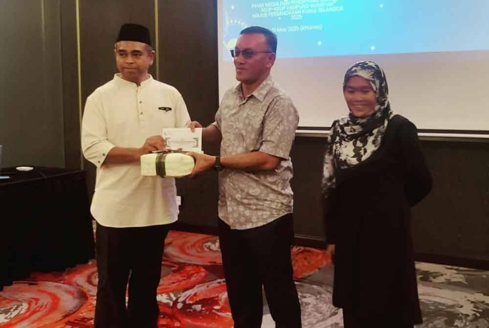 Mohamad Yusli (tengah) menyampaikan cenderahati kepada salah seorang penerima pada Program Nur Ramadan: Menyantuni Media dan Pendayung Santuari Kelip-Kelip Kampung Kuantan pada malam Khamis.