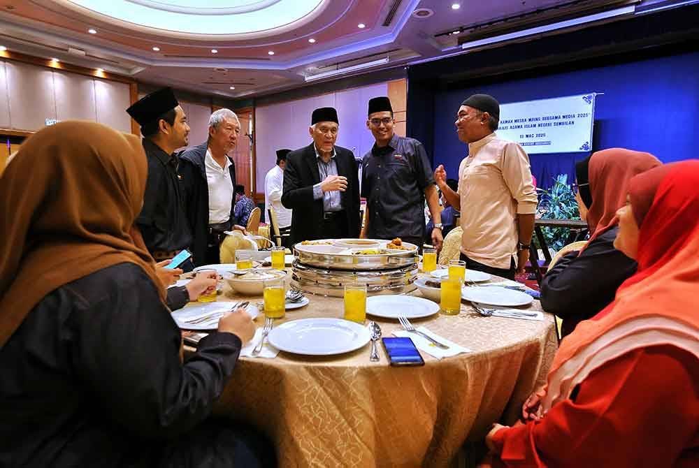 Abdul Aziz (berdiri, tiga dari kanan) beramah mesra dengan pengamal media di Negeri Sembilan pada majlis berbuka puasa di Seremban pada Khamis.