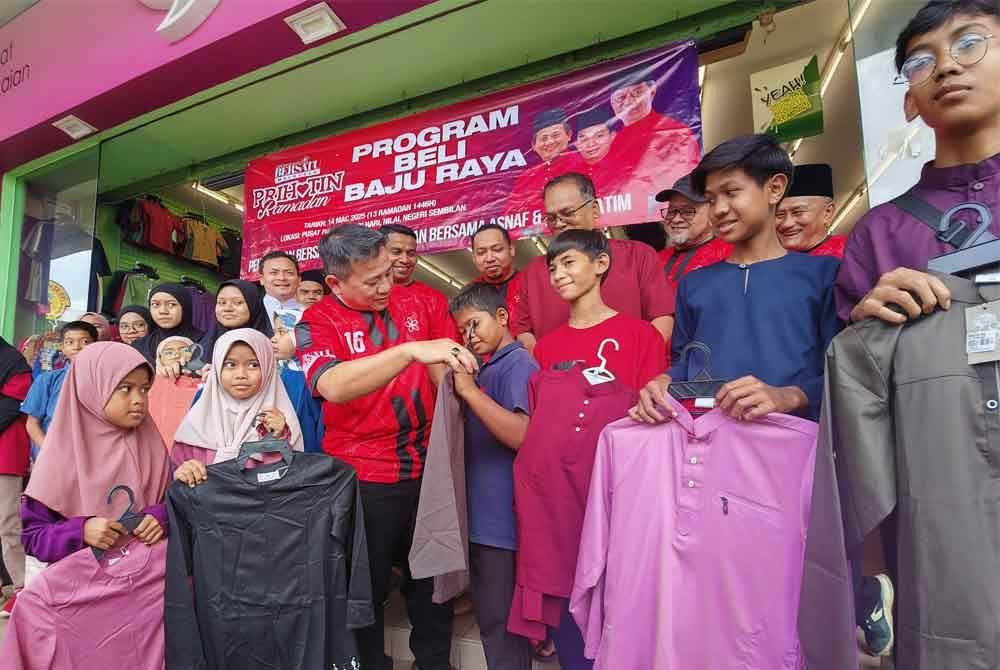 Tun Faisal (tengah) melihat baju Melayu yang dipilih salah seorang penerima bantuan daripada Bersatu pada Program Membeli Baju Rayas Asnaf di Nilai.