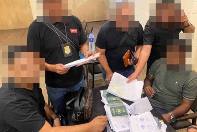 Sekumpulan pegawai JIM melakukan siasatan dan semakan pasport yang dirampas daripada seorang ejen haram warga asing. Foto: JIM.