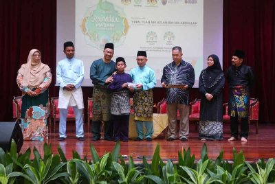 Nik Azlan (empat dari kanan) dan Zamri (tiga dari kiri) menyampaikan sumbangan kepada pelajar daripada golongan memerlukan dalam program Ramadan Madani YAPEIM di Universiti Malaya, Kuala Lumpur pada Khamis.