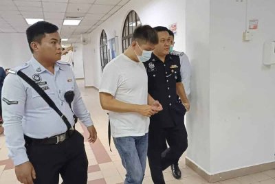 Tertuduh (dua dari kiri) diiringi polis ketika tiba di Mahkamah Majistret Johor Bahru pada Jumaat.