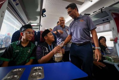 Mohd Rani meluangkan masa beramah mesra bersama penumpang pada Program Sajian Kasih Ramadan: Edaran bubur lambuk kepada penumpang KTMB sempena ulang tahun ke-140 tahun KTMB di Stesen Pulau Sebang, hari ini. - Foto: Bernama