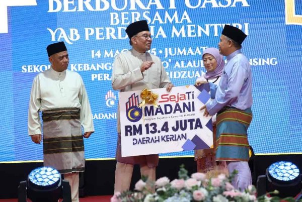 Anwar (tengah) menyampaikan peruntukan Sejati Madani sempena Majlis Berbuka Puasa Madani Peringkat Negeri Perak di Sekolah Kebangsaan Dato' Alauddin, Selinsing di sini pada Jumaat.