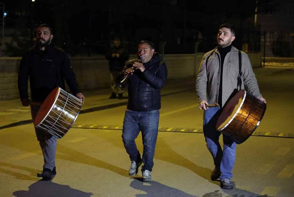Sekumpulan lelaki berjalan sambil memukul gendang untuk mengejutkan penduduk bersahur di Ankara. Foto Xinhua