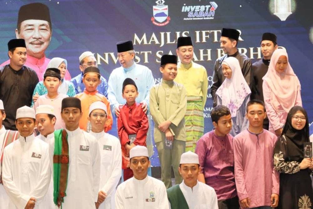 Anifah (empat dari kiri belakang) dan Hajiji (tiga dari kanan) ketika bersama kanak-kanak yatim semasa Majlis Berbuka Puasa Sabah Invest Berhad di Kota Kinabalu.