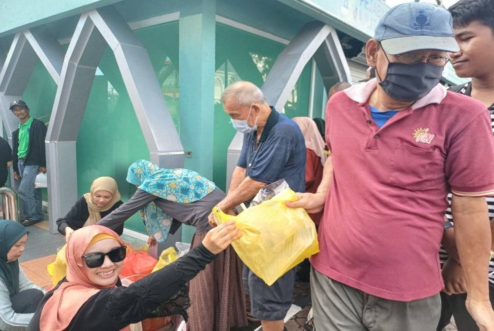 Noordeyana mengagihkan juadah berbuka puasa kepada penerima.
