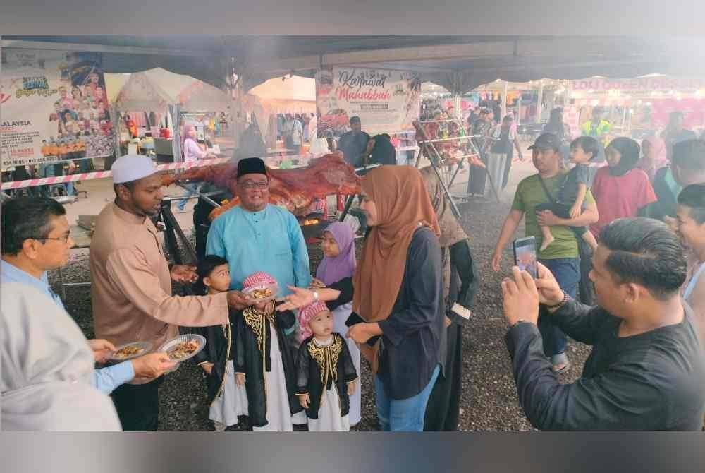 Orang ramai berbaris bagi mendapatkan hidangan lembu golek yang diedarkan secara percuma.