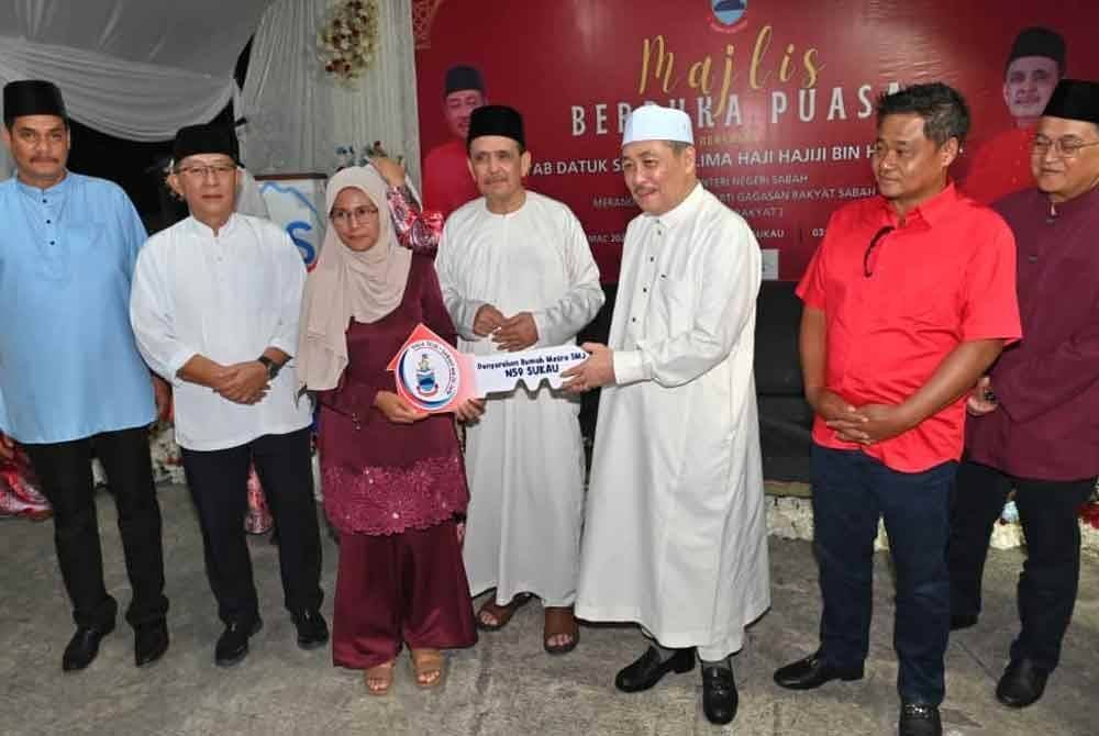 Hajiji menyerahkan replika kunci rumah SMJ DUN Sukau kepada penerima pada Majlis Berbuka Puasa di perkarangan Masjid Tun Juhar Sukau, Kinabatangan.
