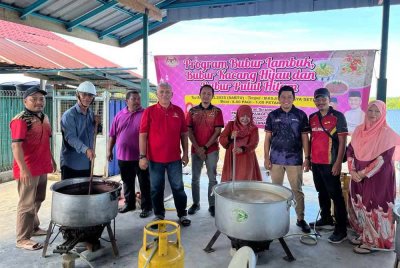 Zainun (empat dari kanan) bersama-sama bergotong royong memasak bubur di Masjid AL Hasanah, Kampung Jaya Setia di sini pada Sabtu.