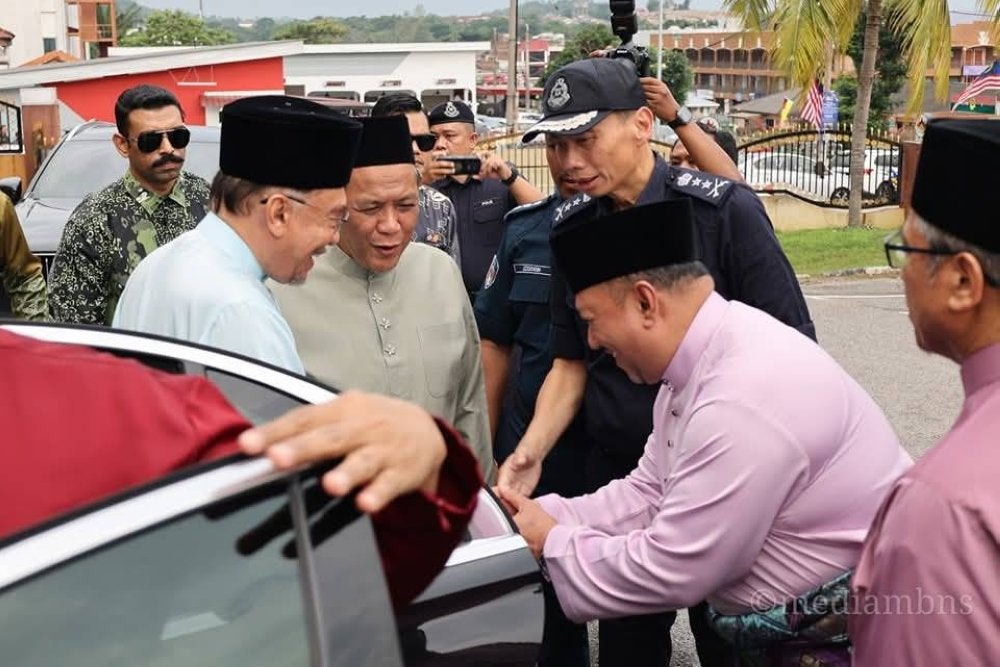 Aminuddin (dua dari kiri) menyambut kehadiran Anwar pada Majlis Berbuka Puasa di Tampin pada Ahad.