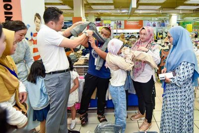 Muhammad Daniel Asyraf (dua dari kiri) dan Nur Fatahul Ashikin (dua dari kanan) masing-masing dibantu Dexter (kiri) dan Redonah (kanan) mencuba pakaian baharu yang dibeli di sebuah pasar raya di Likas, Kota Kinabalu.