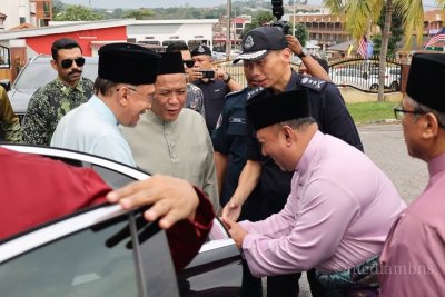 Aminuddin (dua dari kiri) menyambut kehadiran Anwar pada Majlis Berbuka Puasa di Tampin pada Ahad.