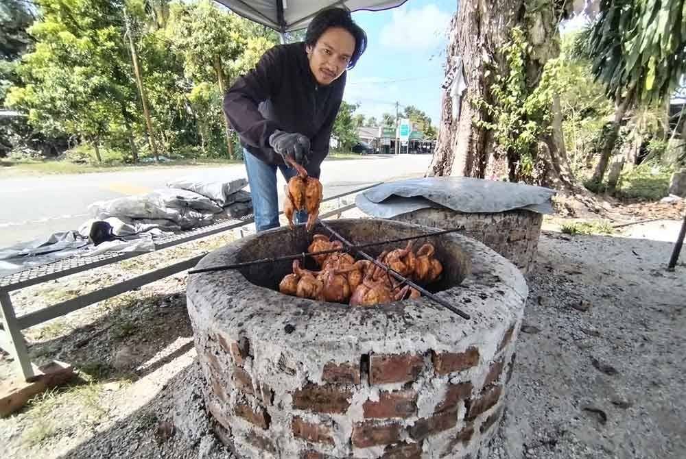 Ariff Haiqal menunjukkan kaedah memanggang 'ayam telaga' yang dijual di Kampung Kepala Gajah, Besut.