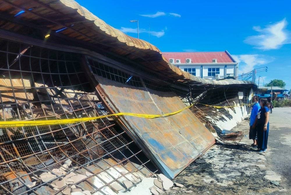 Liong Lam dan isterinya, Lee Ai Choo melihat kedai mereka yang terbakar di Pekan Jitra pada Isnin.