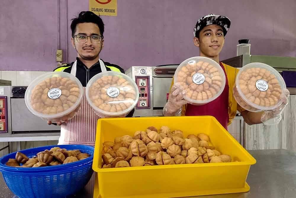 Muhammad Najmi (kanan) dan Arif Fathilah menunjukkan kuih baulu yang dihasilkan di bengkel mereka di Melaka Pindah. Foto Bernama