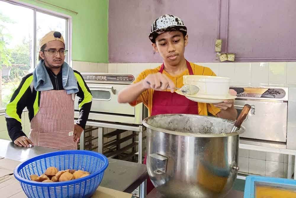 Muhammad Najmi (kanan) dan Arif Fathilah ketika menjalankan proses membuat kuih baulu di bengkel mereka di Melaka Pindah. Foto Bernama