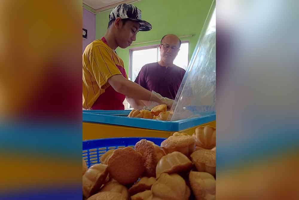 Hee Sem (kanan) melawat bengkel perusahaan kuih baulu yang dijalankan oleh Muhammad Najmi bersama abang sepupunya, Arif Fathilah di bengkel mereka di Melaka Pindah pada Selasa. Foto Bernama