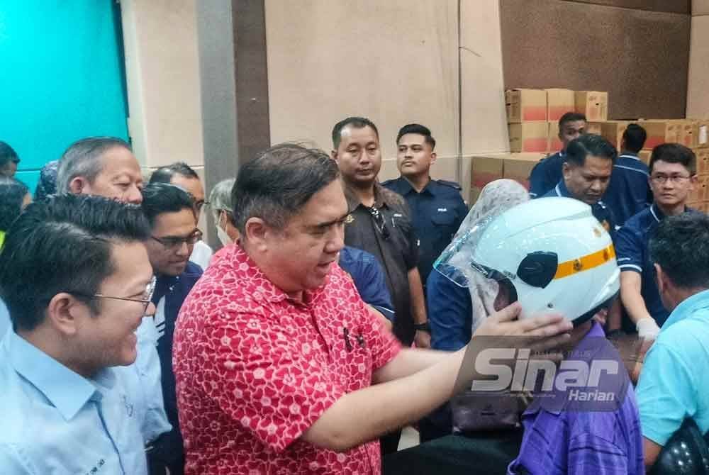 Anthony Loke (dua dari kiri) memakaikan topi keledar baharu yang diagihkan kepada pengguna pada Program Pertukaran Topi Keledar di Dewan Utama Majlis Daerah Jerantut hari ini. - FOTO: SINAR HARIAN