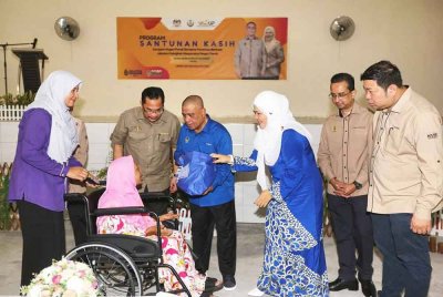 Saarani (tiga dari kiri) bersama Salbiah menyantuni salah seorang penerima sumbangan bakul makanan Program Santunan Kasih Kerajaan Negeri Perak pada Selasa.