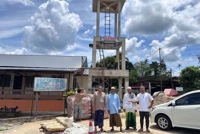 Shazrul Anuar (kanan) berdiri bersama jemaah dan ahli jawatan kuasa berdiri di hadapan Masjid Kampung Jak, Ajil, Hulu Terengganu.