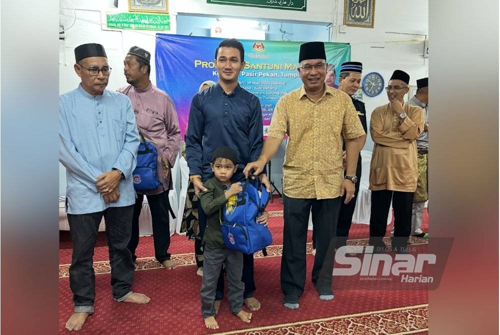Che Roslan (tengah) menyampaikan sumbangan kepada murid Tabika Perpaduan.