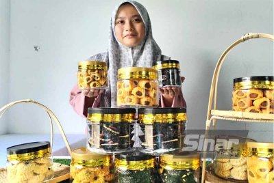 Nur Solehah menunjukkan biskut raya yang dijual pada harga lebih rendah berbanding pasaran.