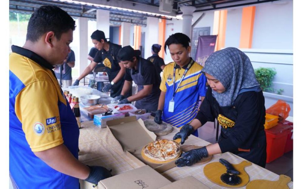 Pelajar UniKL menyiapkan pizza untuk majlis iftar.