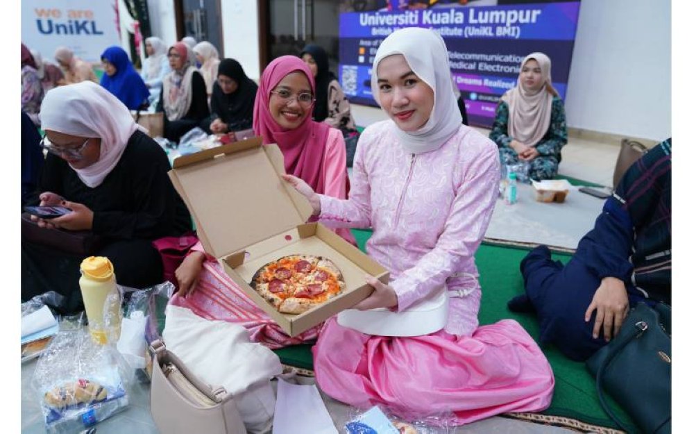 Pelajar UniKL berbuka puasa bersama pizza yang disediakan.