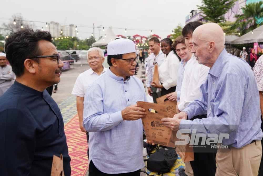 Mohd Fauzi (dua dari kiri) diiringi Hussamuddin (dua dari kiri) mengagihkan cenderahati kepada tetamu antarabangsa pada Program Iftar Ala Madinah di Dataran Karangkraf pada Rabu.