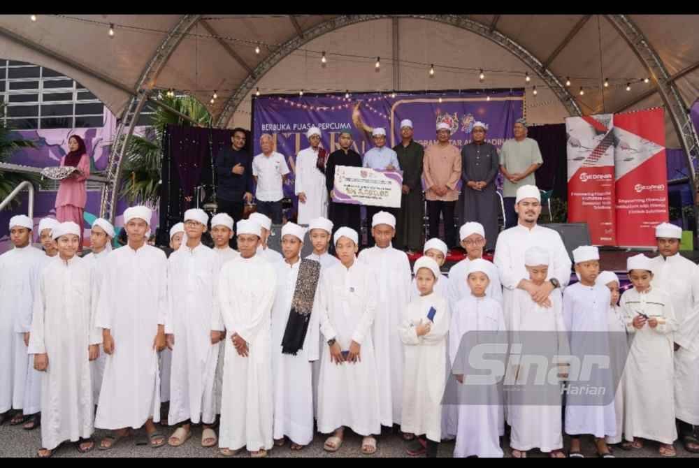 Mohd Fauzi (lima dari kanan) dan Hussamuddin (dua dari kiri) bergambar bersama pelajar tahfiz selepas Majlis Penyampaian Sumbangan pada Program Iftar Ala Madinah.