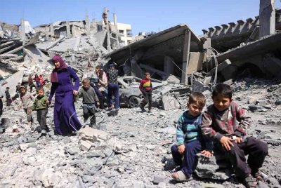 Orang ramai berjalan di celah runtuhan sebuah bangunan yang musnah dalam serangan udara Israel di Jabalia, Genting Gaza, - AFP