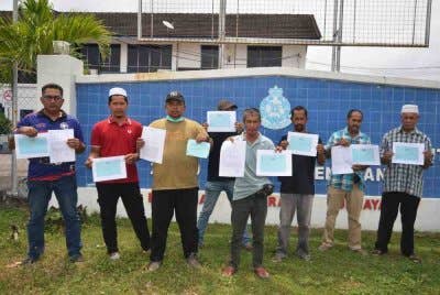 Nasuhaimi (tiga kiri) bersama sebahagian pesawah dari lapan kampung di Hulu Besut menunjukkan salinan laporan polis dan resit jualan masing-masing selepas mereka membuat laporan polis di Balai Polis Kampung Raja pada Rabu. Foto Bernama