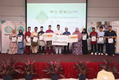 Ameer Ali (tengah) bersama Mohamad Fauzan (enam dari kanan) bergambar dengan penerima sumbangan Ramadan Madani YAPEIM pada Rabu.